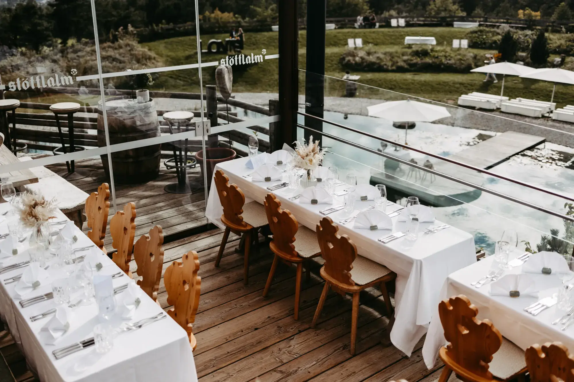 Festlich gedeckte Tafeln mit Tiroler Holzstühlen auf der Terrasse der Stöttlalm mit Blick auf den Stöttlalmsee