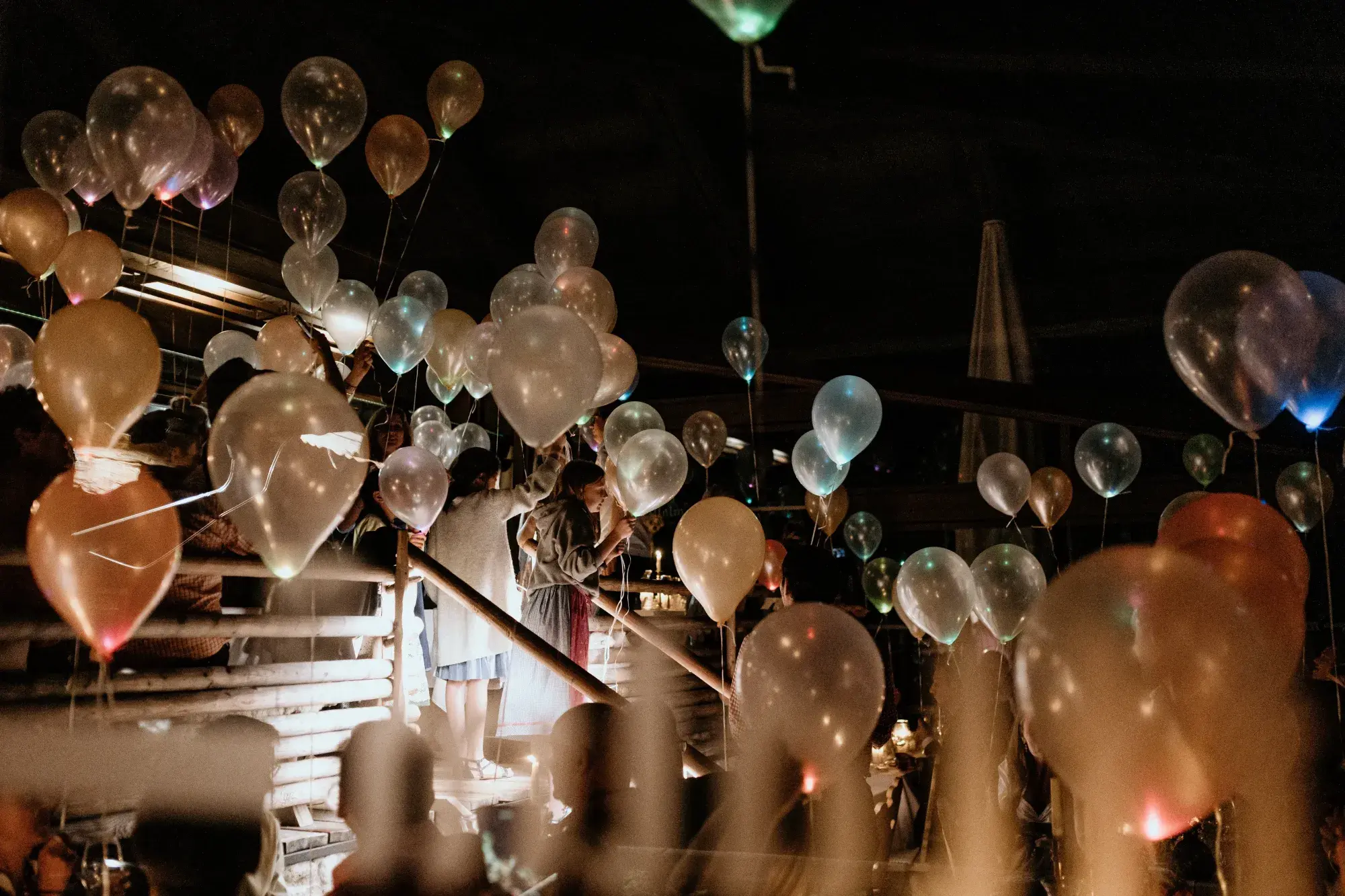 Geburtstagsfeier mit leuchtenden Luftballons am Abendhimmel über der Terrasse der Stöttlalm in Mieming