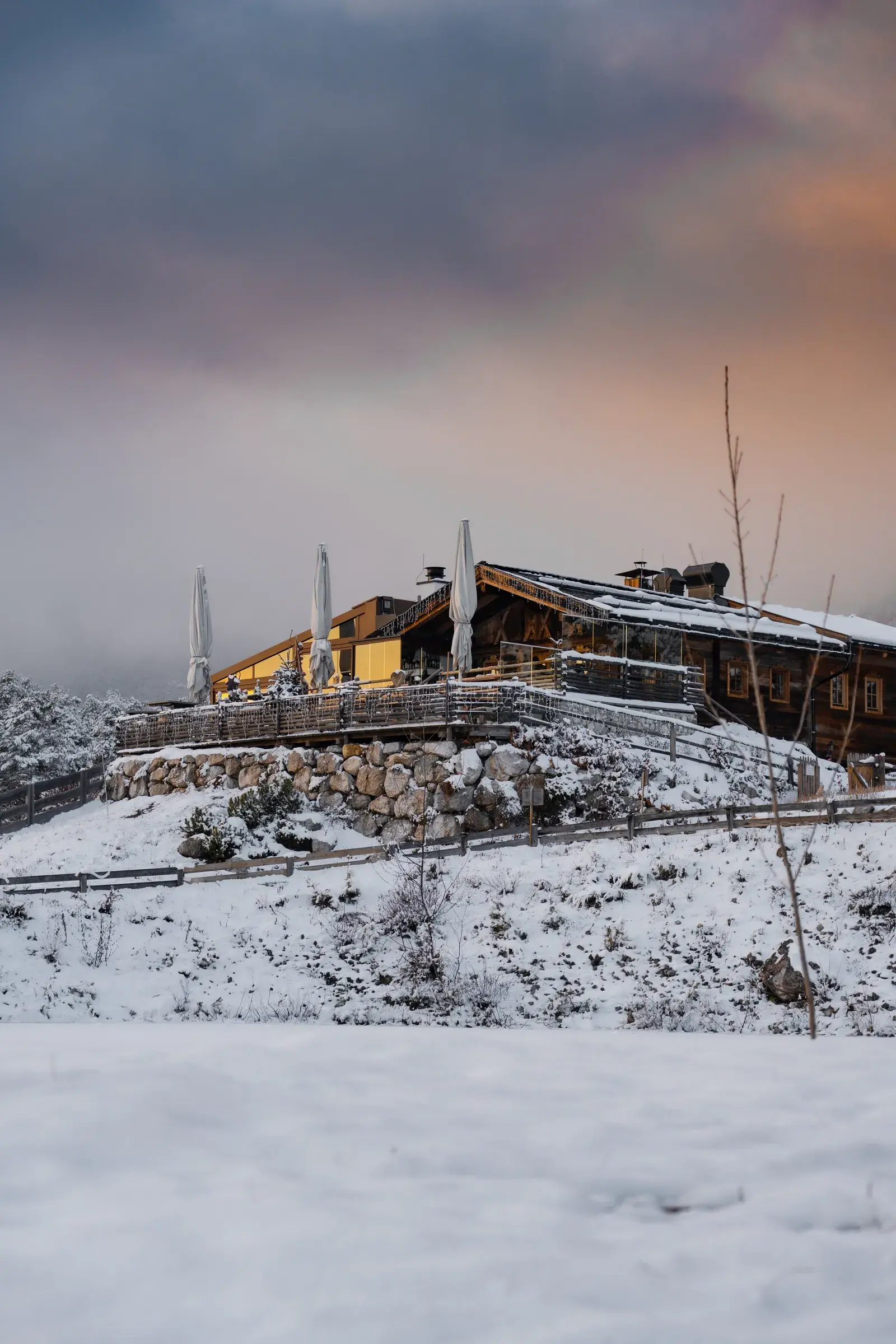 Verschneite Stöttlalm mit Sonnenterrasse für Weihnachtsfeiern im Winter vor der Mieminger Kette in der Dämmerung